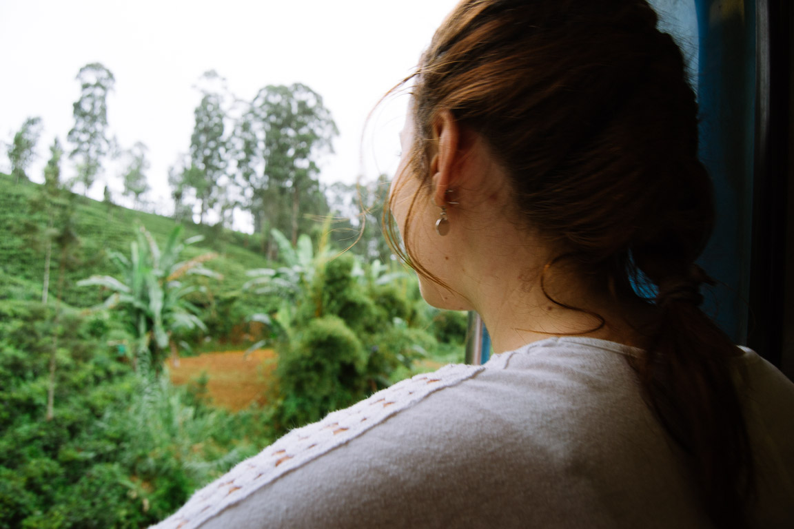 Girl looking out train window at tea plantations
